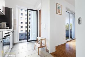 a white kitchen with a stool in a room with windows at PINEAPPLE APARTMENTS - Zwinger I - 80qm - 1x free parking in Dresden +11 photos