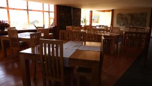 jadalnia z drewnianymi stołami, krzesłami i oknami w obiekcie Coyhaique River Lodge w mieście Coihaique