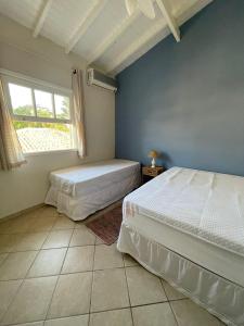 two beds in a room with a window at Casa em condominio na Praia de Juquehy in São Sebastião