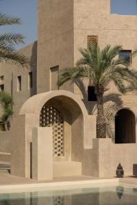 a building with a palm tree next to a swimming pool at Bab Al Shams, A Rare Finds Desert Resort, Dubai in Dubai