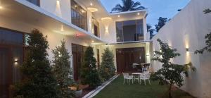 uma casa com um jardim com cadeiras e uma mesa em Hemalie Resort Mirissa em Mirissa