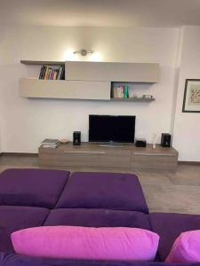 sala de estar con sofá púrpura y TV en Appartamento Montegrappa in centro a Varese, en Varese