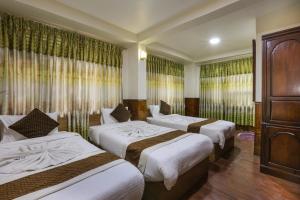 una habitación de hotel con 3 camas y cortinas en Hotel Sekai, en Katmandú