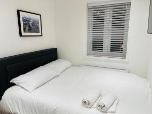 a white bed with two towels on top of it at Riverside Premium En suite Double Room E14 in London