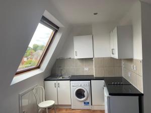 una cocina con lavadora y secadora y una ventana en Studio Flat en Hatch End