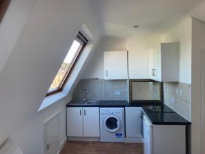 a kitchen with a washing machine and a window at Studio Flat in Hatch End