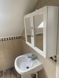 a bathroom with a white sink and a mirror at Studio Flat in Hatch End +2 photos