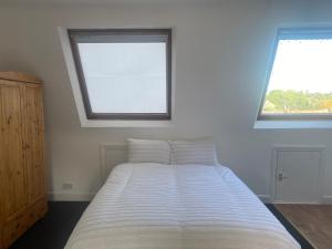 a bedroom with a large bed with two windows at Studio Flat in Hatch End