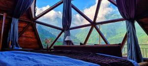 a bedroom with a large window with a view of mountains at Starlit Dome Mcleodganj in McLeod Ganj