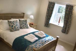 1 dormitorio con 1 cama con 2 toallas en Lake Cottage , Middleton Hall Estate, en Smeafield