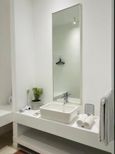 a white bathroom with a sink and a mirror at Saffron Robes Living in Hikkaduwa