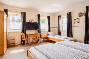 a bedroom with two beds and a table and a desk at Zum Spitzbuam in Attenkirchen