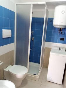 a bathroom with a toilet and a shower with blue tiles at Casa vacanze sul mare in SantʼAlessio Siculo