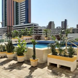 a pool on the roof of a building with potted plants at Via Venetto Apt 1302 Meireles Fortaleza in Fortaleza