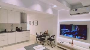 a kitchen with a table and a tv on a wall at STAY Mezarina Apt 2 in Ayia Napa
