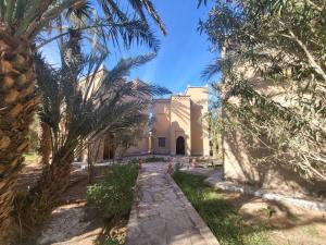 un camino frente a un edificio con palmeras en hotel jnane la kasbah 