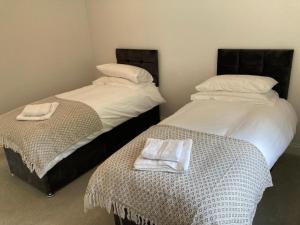 two beds with towels on top of them in a room at Oak Lodge in Stapleford Tawney