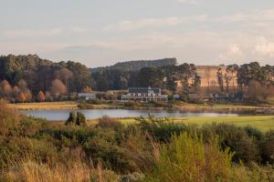 Blick auf einen See mit einem Gebäude im Hintergrund in der Unterkunft Gowrie Farm Golf Lodge in Nottingham Road