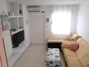 een woonkamer met een bank en een tv bij Bungalow con Patio y Terraza Solárium in Torrevieja