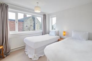 two beds in a room with two windows at Host & Stay - Coast Farm Cottage in Marske-by-the-Sea