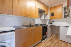a kitchen with wooden cabinets and a sink and a dishwasher at JOIVY Bright apt in West Hampstead in London