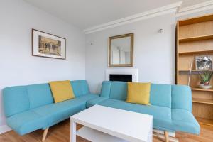 a living room with a blue couch and a table at JOIVY Bright apt in West Hampstead in London