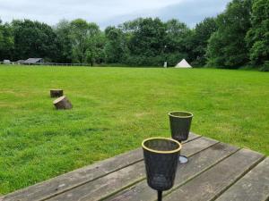 two black buckets sitting on a wooden table next to a field at Glamping in style Bell tent in Ifield