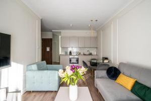 sala de estar con sofá y mesa con flores en Mennica Residence by Golden Apartments, en Varsovia