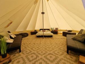 a room with a tent with couches and a bed at Glamping in style Bell tent in Ifield