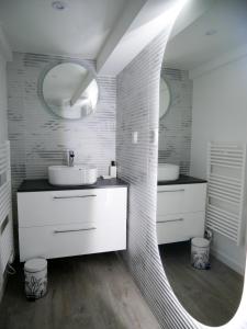 een witte badkamer met een wastafel en een spiegel bij *Romance Jacuzzi* Appartement Spa pour les amoureux ou les solos in Deuil-la-Barre