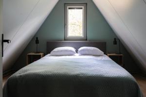 a bedroom with a bed with two pillows and a window at Vakantiehuis Magnolia Nunspeet Veluwe in Nunspeet