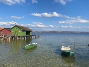 two boats in the water in front of a house at Traumurlaub WestCoast Ammersee 7 Gehminuten zum See in Schondorf am Ammersee