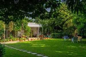 un patio con sillas y árboles y una casa en StayVista's Suman Vatika - Pench - Outdoor Pool, Jacuzzi, Rainshower & Terrace, en Khawāsa