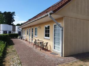 a patio with tables and chairs next to a building at Ferienpark am Darß - Apartmenthaus 2 in Fuhlendorf
