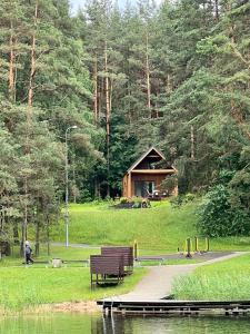 un parque con un banco y una cabaña de madera en Namelis Strazdas, en Molėtai