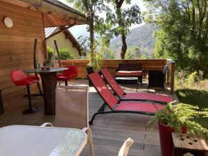 a deck with red chairs and a table and a table at Charmant petit chalet individuel in Briançon