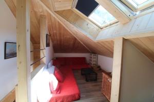a room with a red couch in a attic at Charmant petit chalet individuel in Briançon