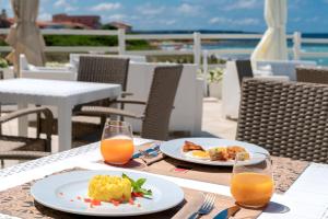 una mesa con dos platos de comida y dos vasos de zumo de naranja en Hotel da Cesare Maluentu, en Putzu Idu