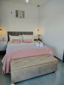un letto con una coperta rosa e un animale di peluche sopra di Guaraípe a Guarapari Altre 18 foto