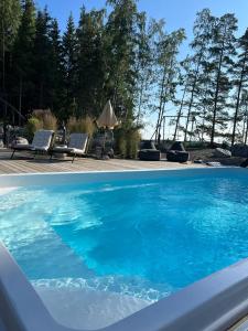a blue swimming pool with two chairs and an umbrella at Beautiful Villa by the sea in Porvoo