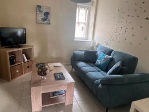 a living room with a blue couch and a coffee table at Le clos de la cote d'Emeraude in Saint-Benoît-des-Ondes