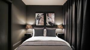 a bedroom with a bed with three pictures on the wall at Midnight by The Heim Residences in Manchester