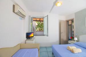 a bedroom with two beds and a tv and a window at La Turrita Apartments in Ischia