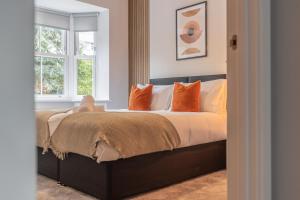 a bedroom with a bed with orange pillows and a window at Green Park House, Private Garage and Parking in Coventry