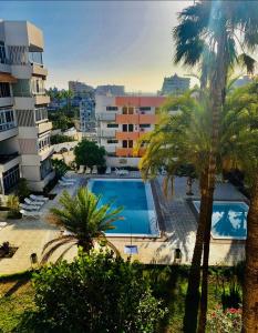 une piscine en face d'un bâtiment avec des palmiers dans l'établissement Ladyhouse Yumbo, à Playa del Ingles