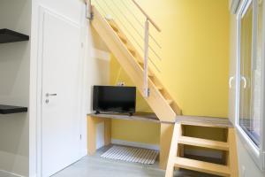 Una sala de estar con paredes amarillas y una escalera con un televisor. en Le domaine du pilat, en Saint-Étienne