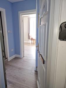 a hallway with blue walls and a wooden floor at Largs Apartment, Spacious & Modern 1 Bed near beach & shops in Largs