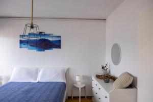a white bedroom with a blue bed and a chair at Lugano Boat Apartment in Lugano
