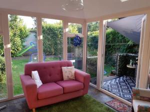 a pink couch sitting in a room with windows at 3 bedroom village house 