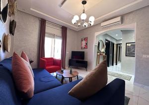 Appartement agréable en plein coeur de Marrakech pour 2 à 4 Personnes في مراكش: غرفة معيشة مع أريكة زرقاء وكرسي احمر